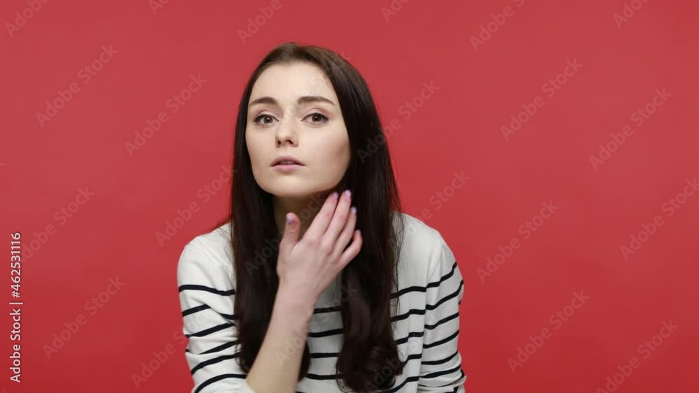Portrait of woman looking in mirror, admiring herself, combing her hair, doing care procedures, wearing casual style long sleeve shirt. Indoor studio shot isolated on red background. Portrait of woman looking in mirror, admiring herself, combing her hair, doing care procedures, wearing casual style long sleeve shirt. Indoor studio shot isolated on red background.