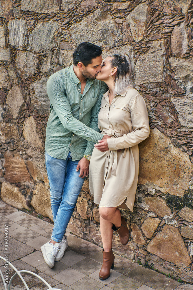 Young Latin male and female couple in love giving each other a kiss between 25 and 35 years old