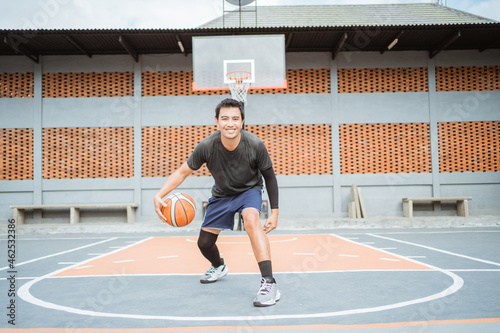 a basketball player performs a low dribble between the legs dribble with the ball while practicing basketball photo
