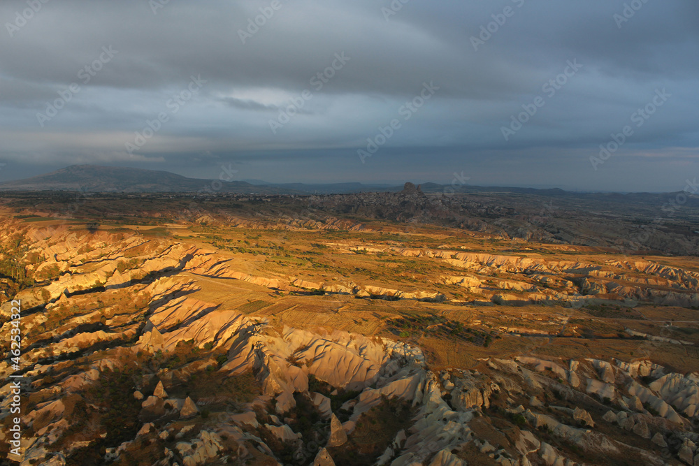  look from above at a yellow-brown rocky valley flooded with evening sun