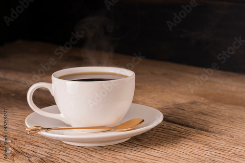 Coffee cup with a black coffee on a wooden table, dark black background