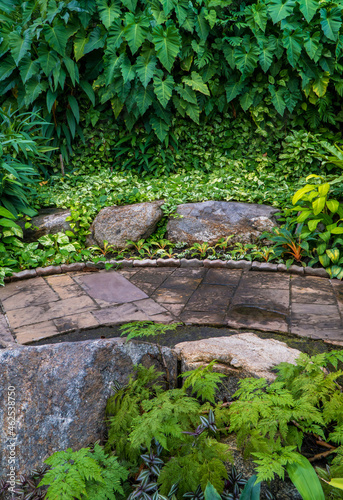 Tropical botanical garden decorated with different shapes of stones with stone pathway. Beautiful botanic park. vertical photo