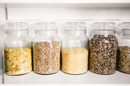 clear pantry jars with grains and healthy ingredients including quinoa buckwheat polenta and barley, simple ingredients concept