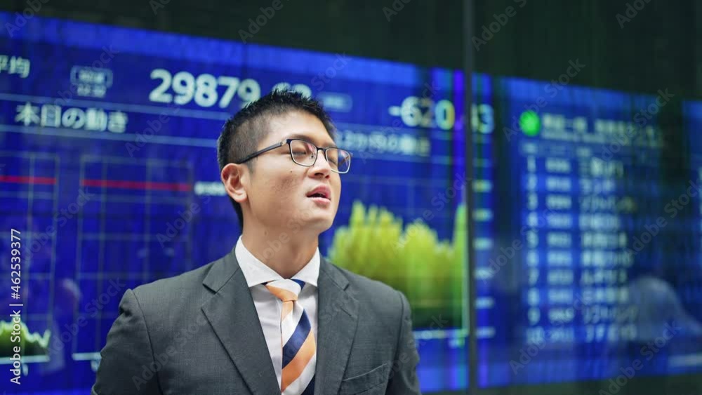 株価ボードの前で落ち込む男性