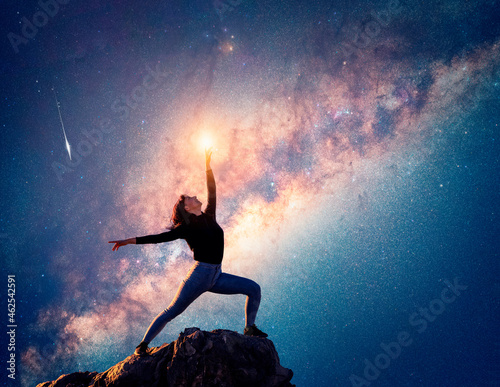 latin woman is dancing or posing on the top of the mountain pointing to the sky and the Milky Way 