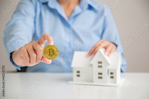 Woman hand holding bitcoin for buying savings home, Investment home bitcoin. Home buying savings concept.