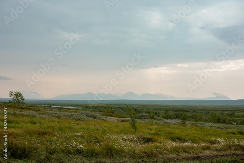 A distant wild plateau in the arctic tundra. Against the background of the distant outlines of the mountains, a cloudy day.
