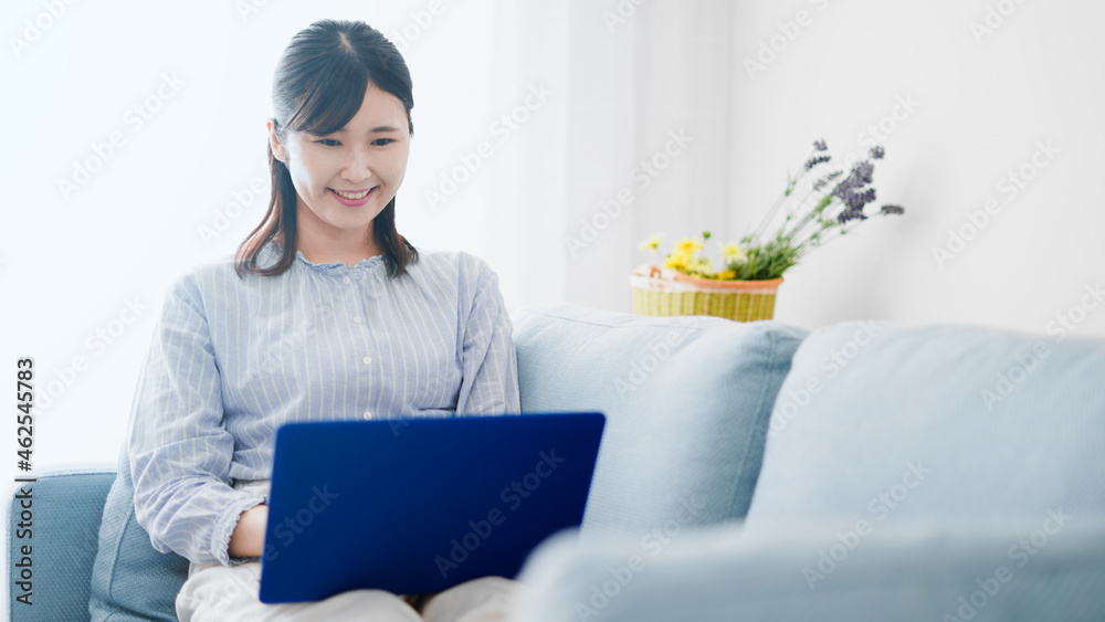ソファーでノートパソコンを使う女性