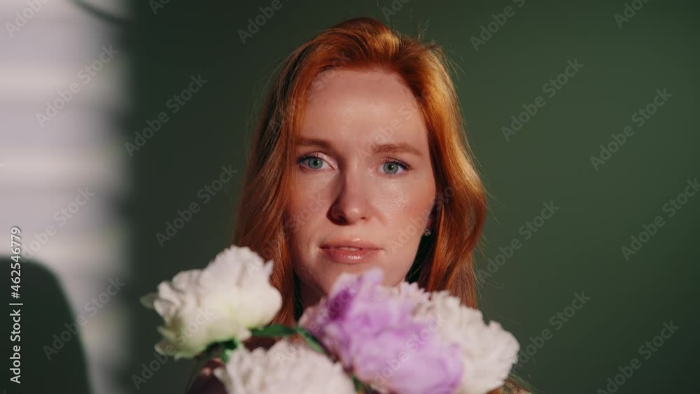 The general plan A beautiful blue-eyed woman with a bouquet of flowers. An attractive red-haired girl looks into the frame, smiles. The sun's glare is reflected on the face. The concept of femininity. The general plan A beautiful blue-eyed woman with a bouquet of flowers. An attractive red-haired girl looks into the frame, smiles. The sun's glare is reflected on the face. The concept of femininity.
