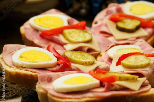 Sandwiches with egg and ham on plates.
