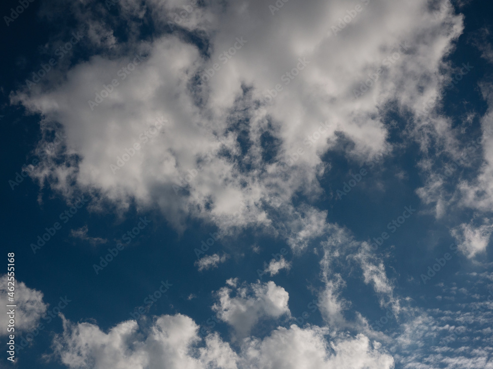Obraz premium White cumulus clouds against a deep blue sky.