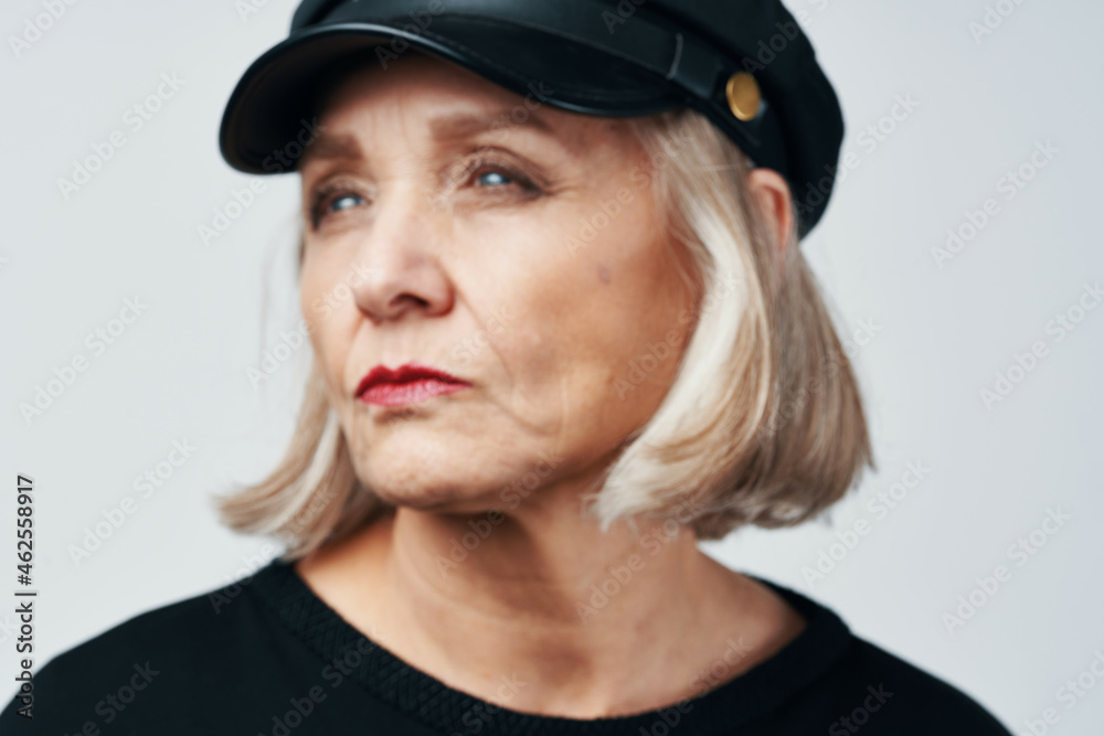 elderly woman in a black hat fashion close-up light background elderly woman in a black hat fashion close-up light background