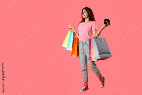 Attractive girl with multicolored paper bags on pink background