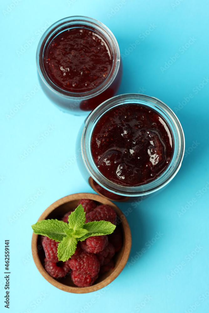 Jars of raspberry jam with ingredients on blue background Jars of raspberry jam with ingredients on blue background