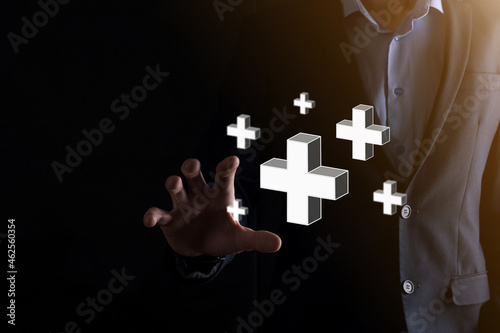 Businessman hold 3D plus icon, man hold in hand offer positive thing such as profit, benefits, development, CSR represented by plus sign.The hand shows the plus sign