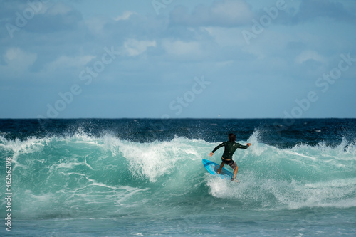 male surfer doing a turn on a wave at the beach in summer on a sunny day