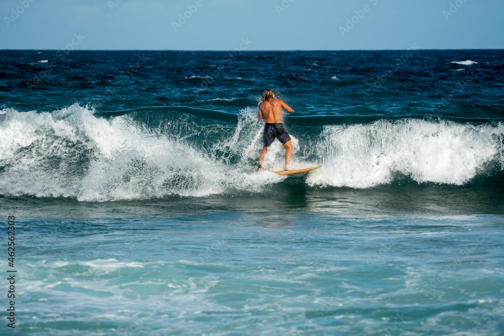 male surfer doing a turn on a wave at the beach in summer on a sunny day
