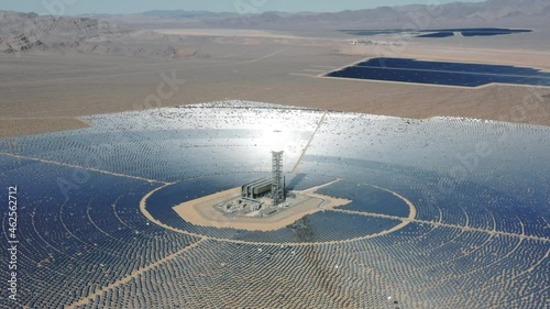 Modern solar power station with tower in aerial view, Concentrated solar power tower, solar farm center in Nipton California and Nevada desert boarder, USA. 4K aerial of sustainable energy generation photo