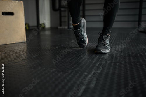Crop shot of man feet in black sport shoes or sneakers moving on gym floor during intensive workout against sports equipment. People and active lifestyle. Aerobics, fitness, indoor sports © Anatoliy Karlyuk