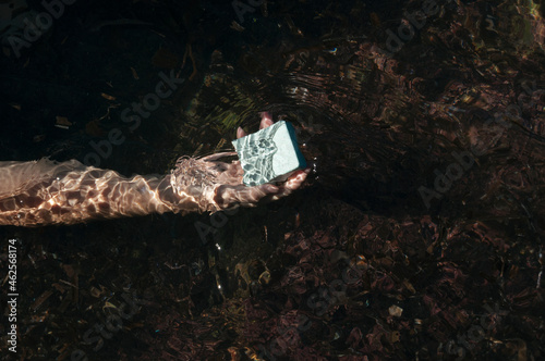Hand holding a bar of soap in sea water