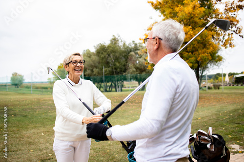 Senior retired people enjoying free time in nature by playing golf and having fun at the golf course.