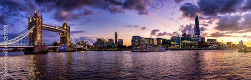 Wide panoramic view of the illuminated skyline of London during colorful autumn dusk from the Tower Bridge along the Thames river to London Bridge