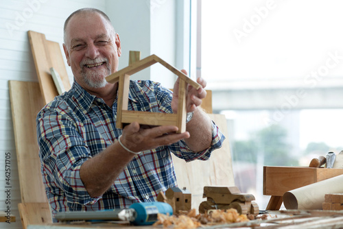 Fototapete Smiling caucasian craftsman made wooden house toys in home workshop