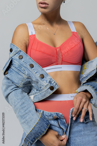 beautiful blonde girl in jeans and lingerie on a gray background