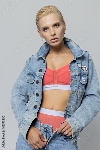 beautiful blonde girl in jeans and lingerie on a gray background