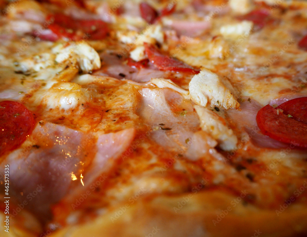 pizza close-up with cheese, pepperoni, bacon and chicken pieces. side view pizza close-up with cheese, pepperoni, bacon and chicken pieces. side view