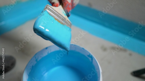 A worker paints a waterproof finishing material with a brush. The bathroom floor in the apartment is under renovation. The worker smears the corner of the wall with waterproofing mortar.