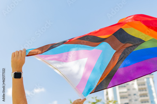 Foto Progress pride flag (new design of rainbow flag) waving in the air with blue sky