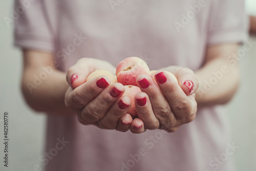Close-up of a woman holding a handful of fresh apricots