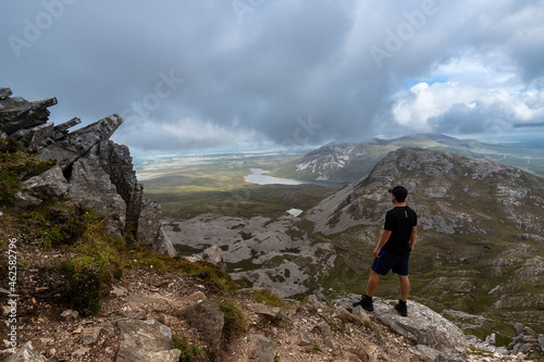 Man standing on top of mountain admiring landscape of Errigal mountain Co. Donegal Ireland © Simon