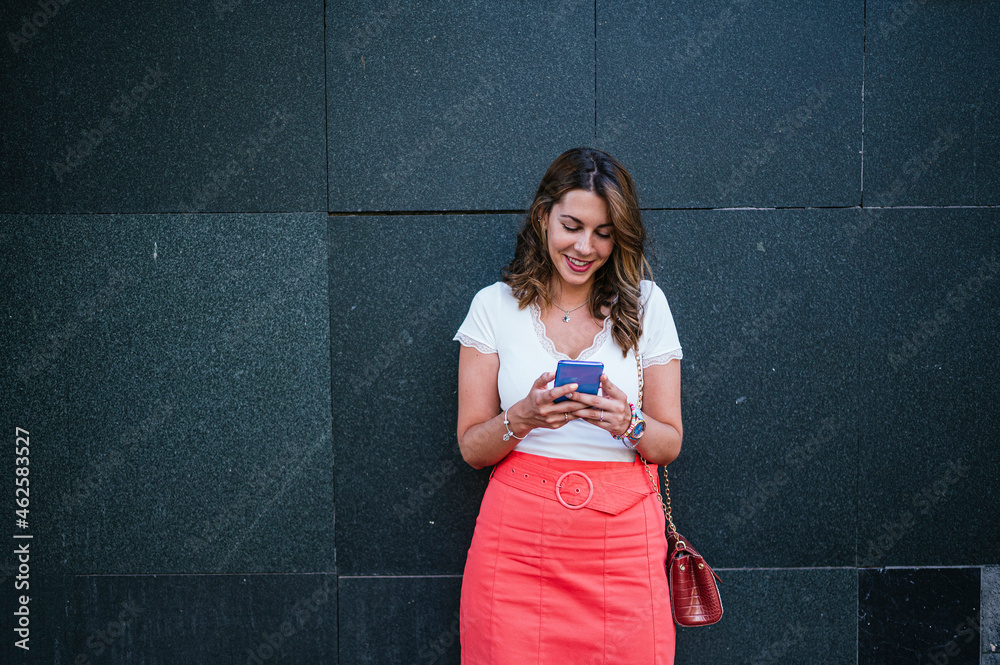 Side view of woman in summer clothes using smart phone and standing in the city. Side view of woman in summer clothes using smart phone and standing in the city.