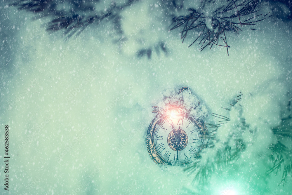 New year and Christmas clock lying on a snow under a fir tree in the forest
