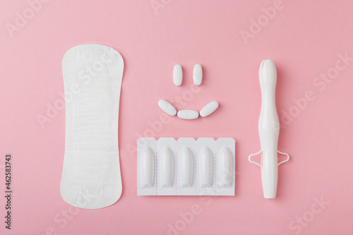 vaginal suppositories, tablets, applicator and sanitary napkin on pink background, treatment of vaginal infections with smile from candidiasis, thrush, sexually transmitted infections. Woman health photo