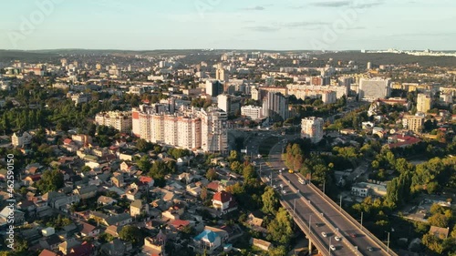 Aerial drone view of Chisinau at sunset. Multiple buildings, road and bridge with cars. Greenery photo