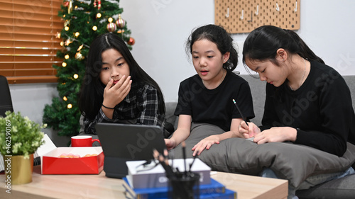 Young asian girls studying online at home together.