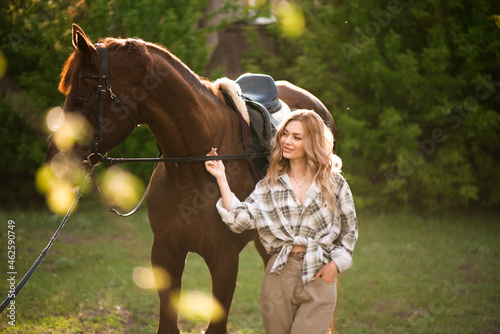 Beautiful girl with her horse and beautiful warm sunset in the spring forest.