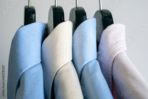 Close-up of hangers with business shirts. Row of colored shirts on a rack. Cloth hanger with casual men shirt.
