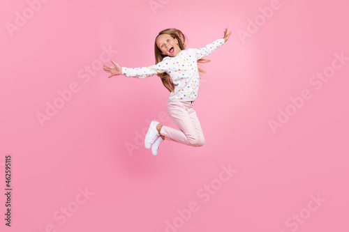 Photo of crazy excited little lady jump open mouth wear dotted pajama pants sneakers isolated pink color background