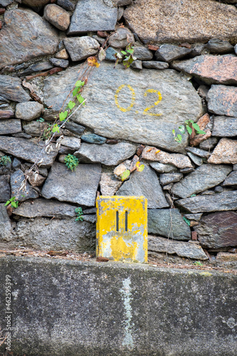 Vertical shot of an old milestone, colored in yellow, located on a street in Novara, Piedmont. photo