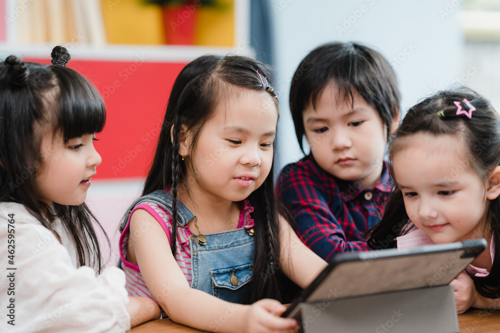 Group of children using tablet in classroom, Multi-ethnic young boys and girls happy using technology for study and play games at elementary school. Kids use technology for education concept. Group of children using tablet in classroom, Multi-ethnic young boys and girls happy using technology for study and play games at elementary school. Kids use technology for education concept.
