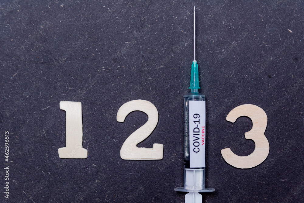 Third covid vaccine dose and jab concept with numbers. Syringe is seen on table as a concept for the 3rd covid-19 vaccine dose, also called booster shot - obrazy, fototapety, plakaty 