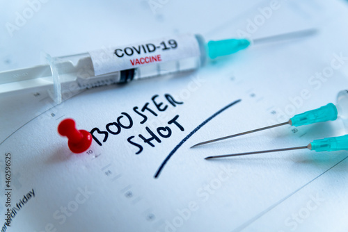 Third covid vaccine dose and jab concept. Three syringes are seen on calendar as a concept for the 3rd covid-19 vaccine dose, also called booster shot, now requested during the vaccination campaign. photo