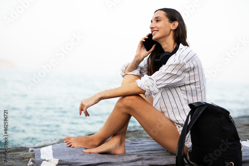 Happy young woman relaxing on the sandy beach. Beautiful woman enjoying a summer day on the beach... © Jelena