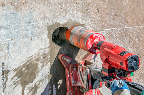 Worker is drilling to concrete wall with core drill machine. Core drills used in metal are called annular cutters. Core drills used for concrete and hard rock generally use industrial diamond grit. photo