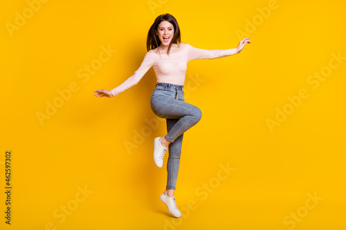 Fototapeta Naklejka Na Ścianę i Meble -  Full size photo of young fun excited smiling crazy girl jumping with flying hair isolated on yellow color background