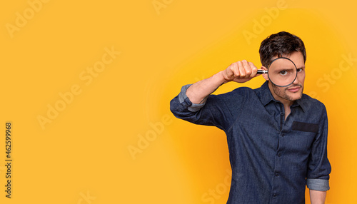 Man holding a magnifying glass in front of his eye